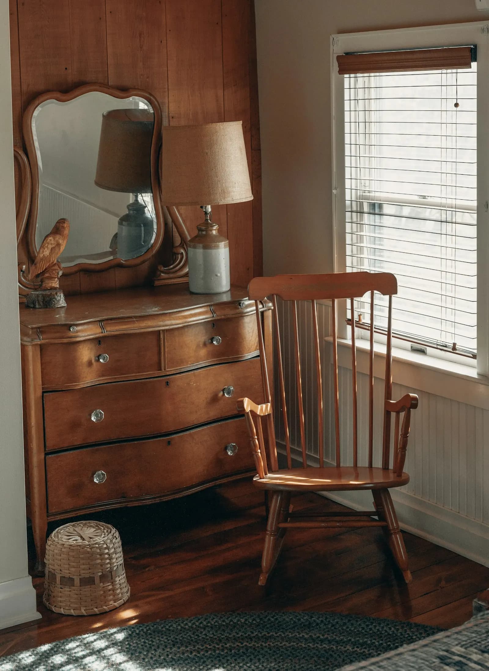 An old wooden dresser with a mirror beside a rocking chair