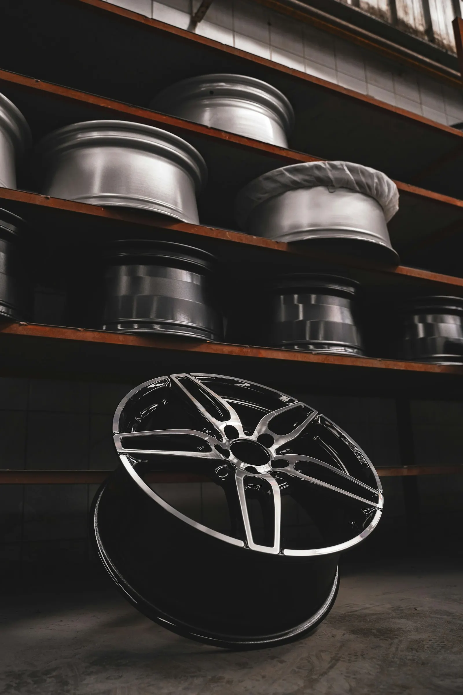 Alloy wheels stacked on shelves, one leaning on the floor