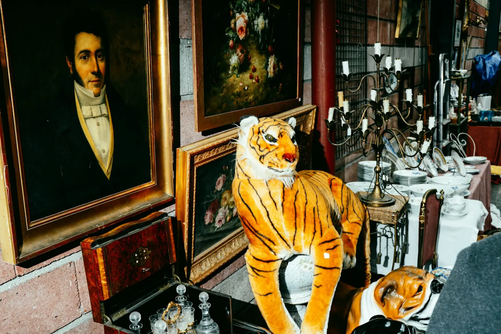 A crowded antique shop with an oil portrait and a toy tiger