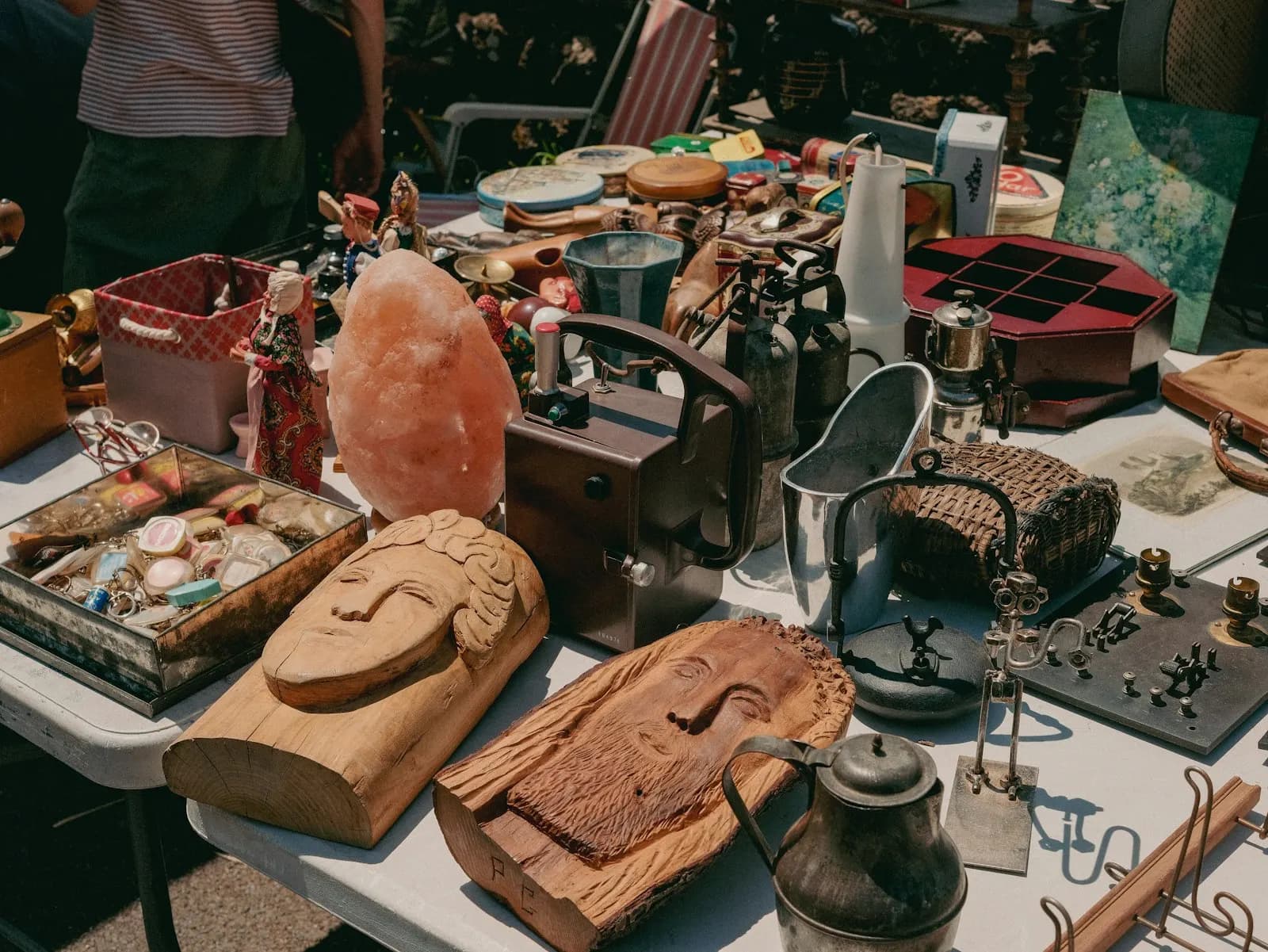 Tables covered in carvings, tins and odds and ends at a sale