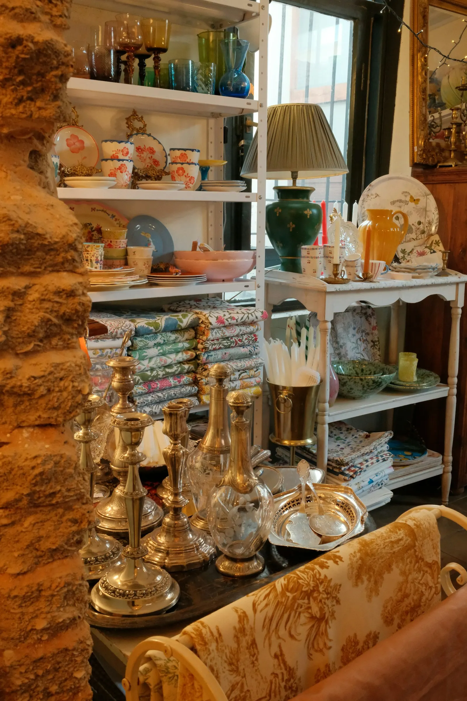 Shelves of glassware, lamps and books for sale