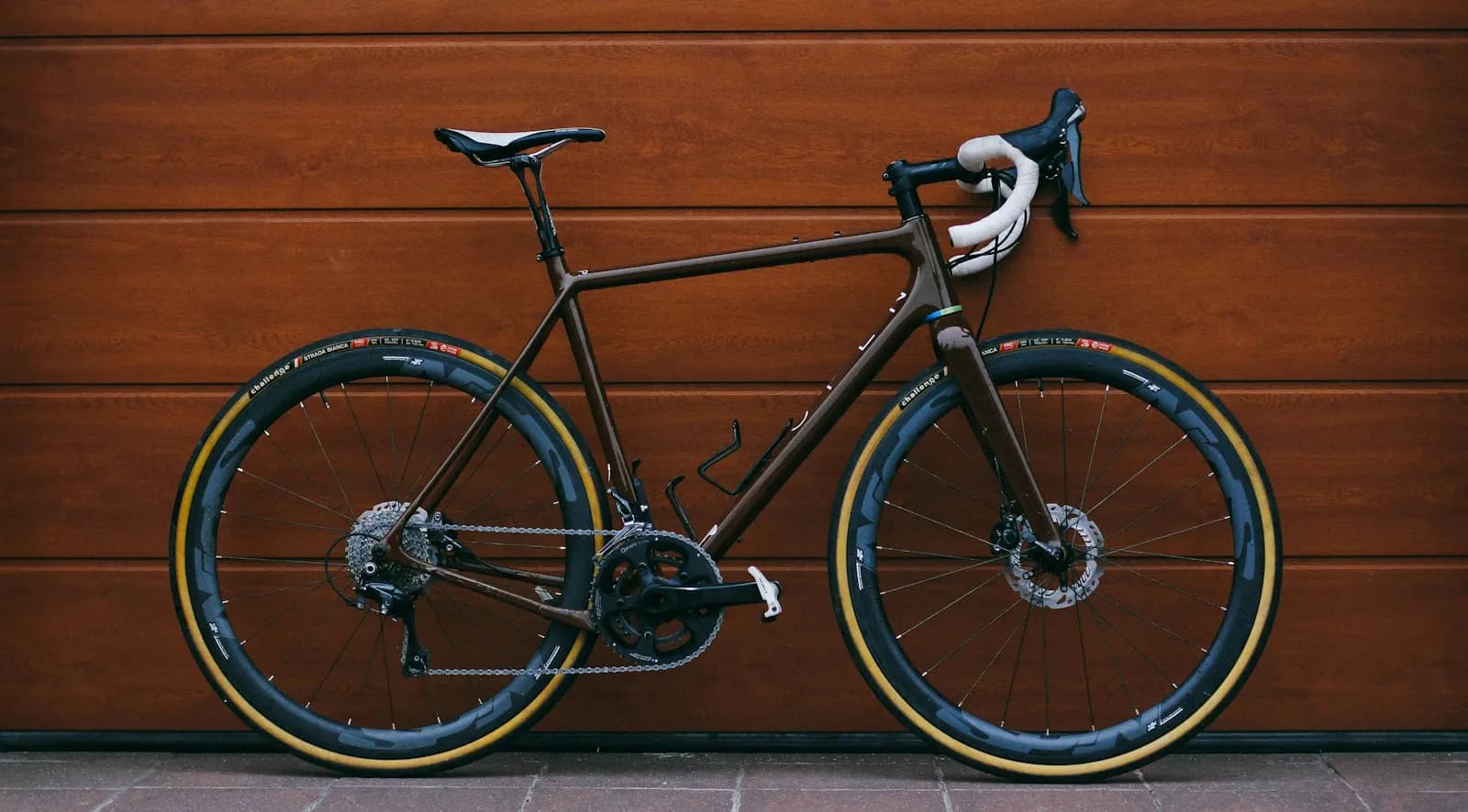 A black road bike leaning against a wooden garage door